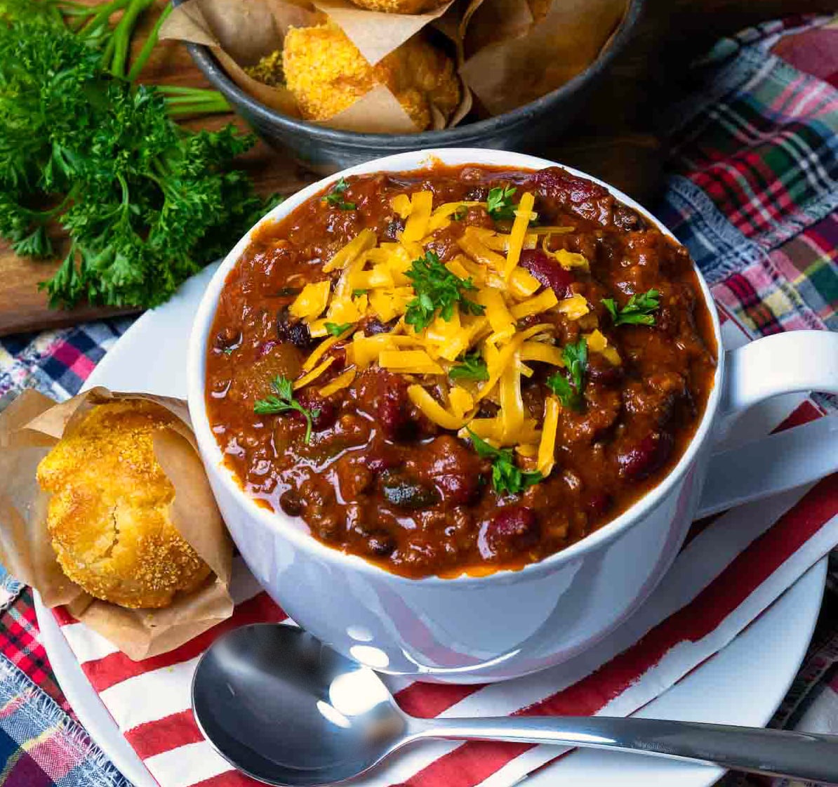 Award Winning Southern Soul Chili served in a bowl topped with cheese and served with muffins.