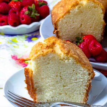 Slice of Southern Pound Cake with berries on a plate with fork ready to be enjoyed.