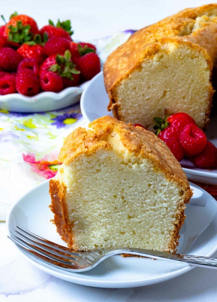 Slice of Southern Pound Cake with berries on a plate with fork ready to be enjoyed.