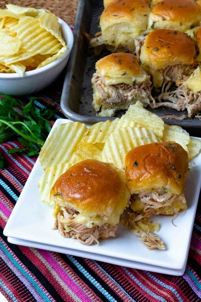 Sliders made with Crock Pot Mississippi Chicken and cheese served with potato chips.
