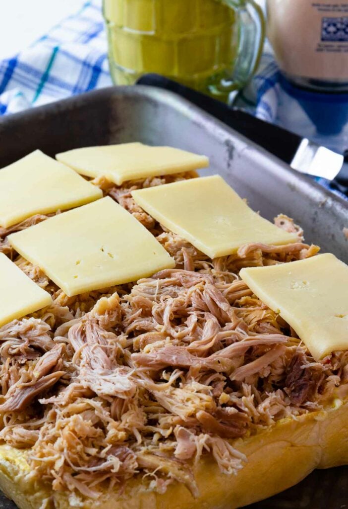 Crock Pot Mississippi Chicken loaded onto slider buns and topped with cheese.