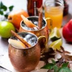 Two Moscow Mule copper mugs filled with spiced pear drink.