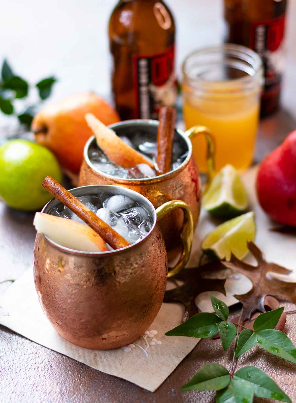 Two Moscow Mule copper mugs filled with spiced pear drink.
