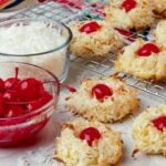 Ambrosia Cookies with red cherries and white coconut on a rack cooking.