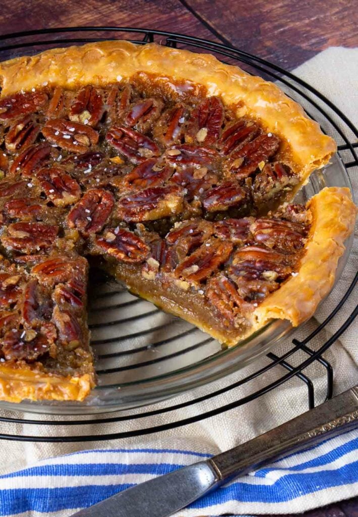 Maple Bourbon Pecan Pie sliced in pie pan on cooling rack.