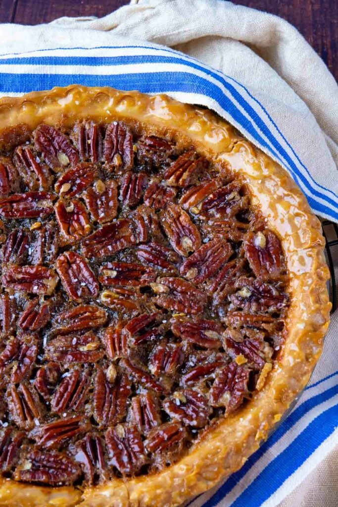 Maple Bourbon Pecan Pie with buttery crust cooling on a tea towel.