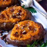 Twice baked sweet potatoes with toasted pecans on a platter with serving fork.