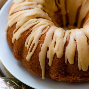 Buttermilk Pound Cake with brown butter icing on a plate with a silver cake cutter.