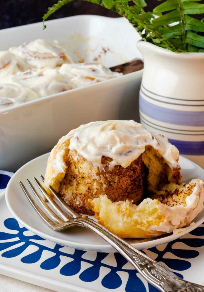 Easy Cinnamon Rolls on a plate with icing cut with a fork.