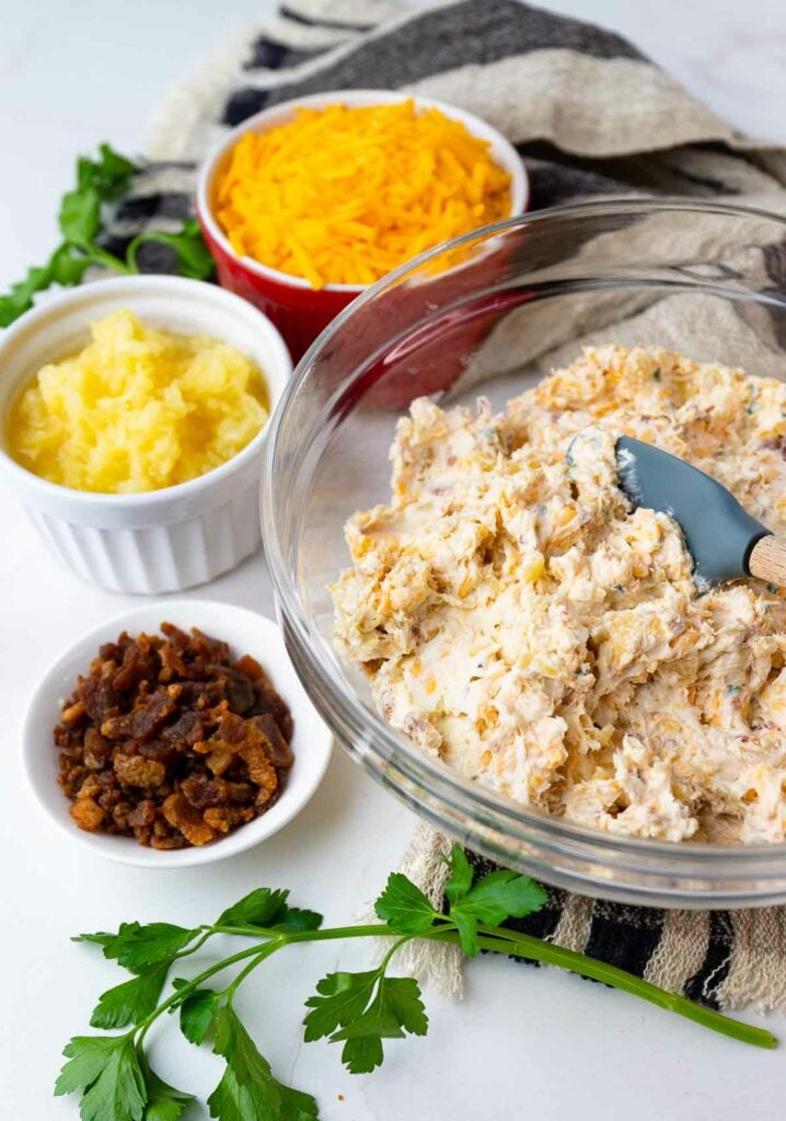 Pineapple Bacon Cheese Ball ingredients with cheese and bacon and spatula.