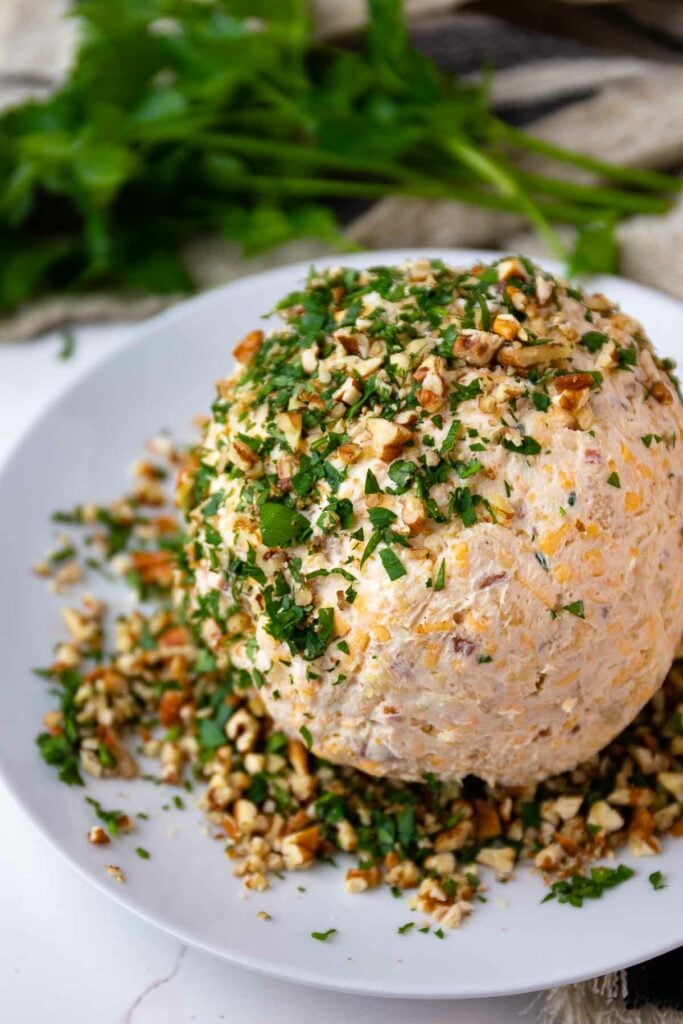 Pineapple Bacon Cheese ball with extra pecans and parsley coating on a plate.