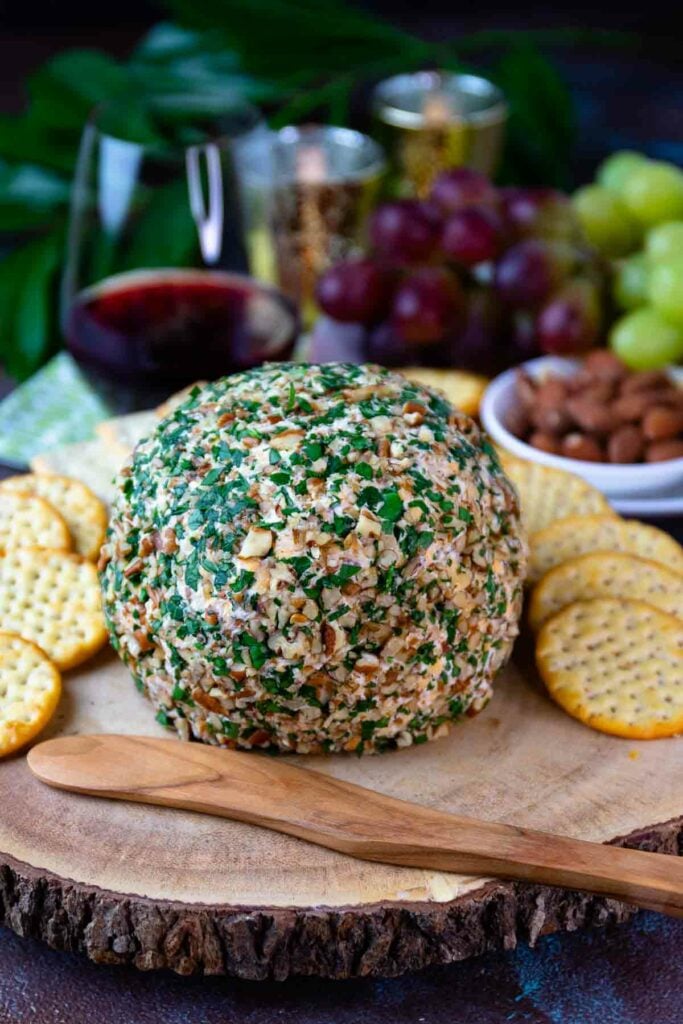 Whole Pineapple Bacon Cheese Ball on a platter with crackers and a wooden knife.
