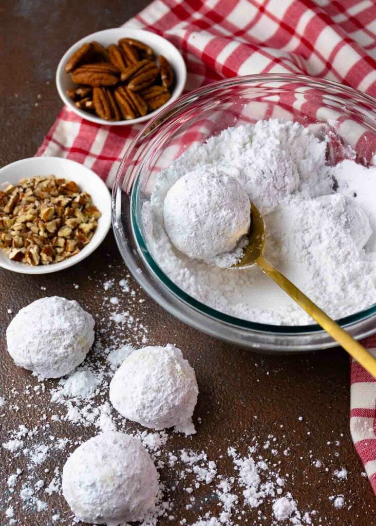 Snowball Cookies with pecans and powdered sugar in a bowl.
