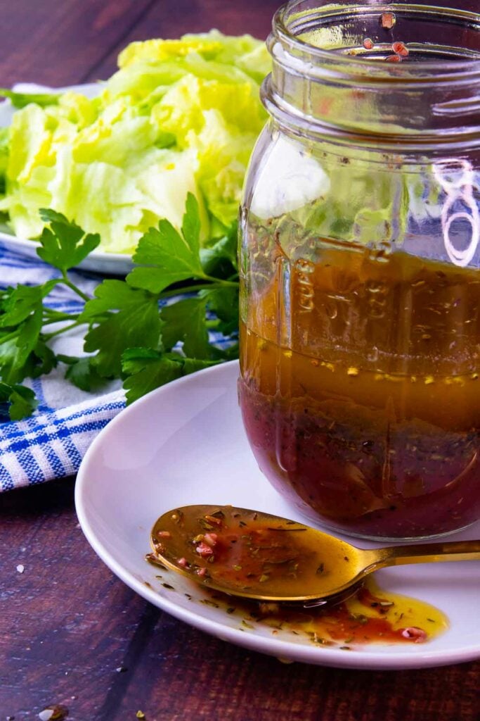 Greek Salad Dressing is homemade and simple. With lettuce and ingredients on a spoon.