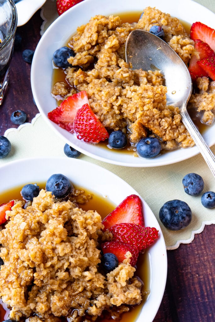 Maple Cinnamon Baked Oatmeal on white plates with fresh blueberries and strawberries.