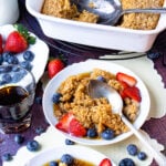 Baked Oatmeal on plates with maple syrup, blueberries and strawberries.