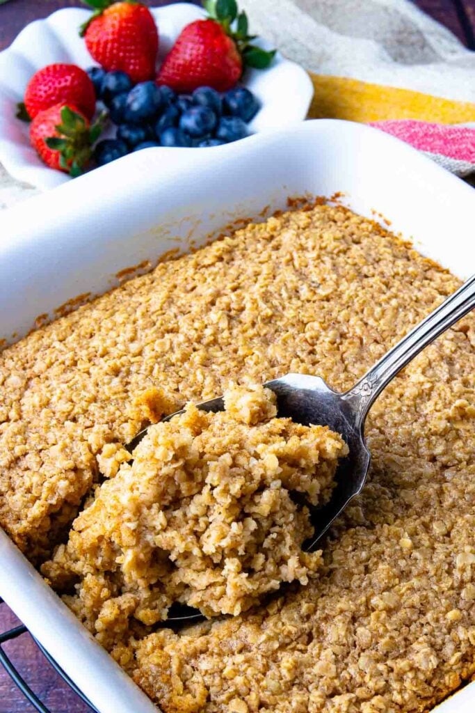 Maple Cinnamon Baked Oatmeal in a white pan with a spoon for serving.