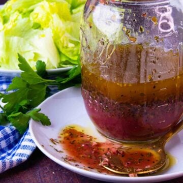 Greek Salad Dressing is homemade and simple. With lettuce and ingredients on a spoon.