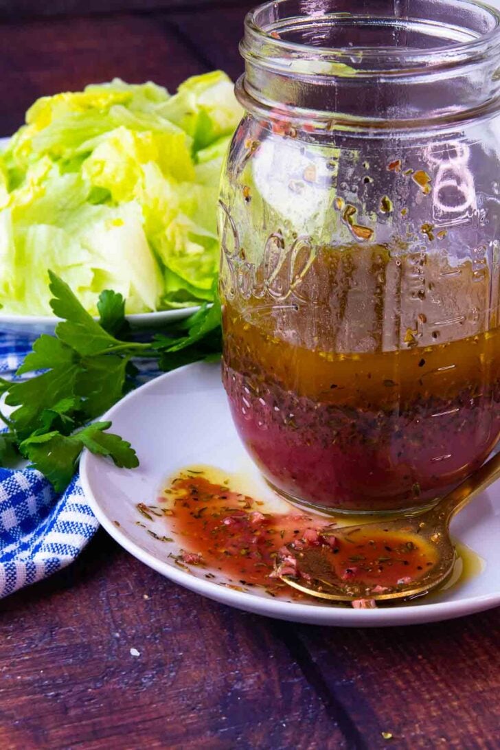 Greek Salad Dressing is homemade and simple. With lettuce and ingredients on a spoon.
