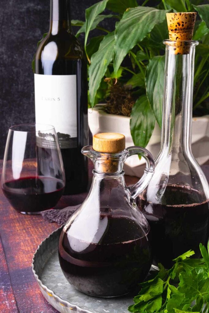 How to make red wine vinegar showing 2 glass bottles and greenery.