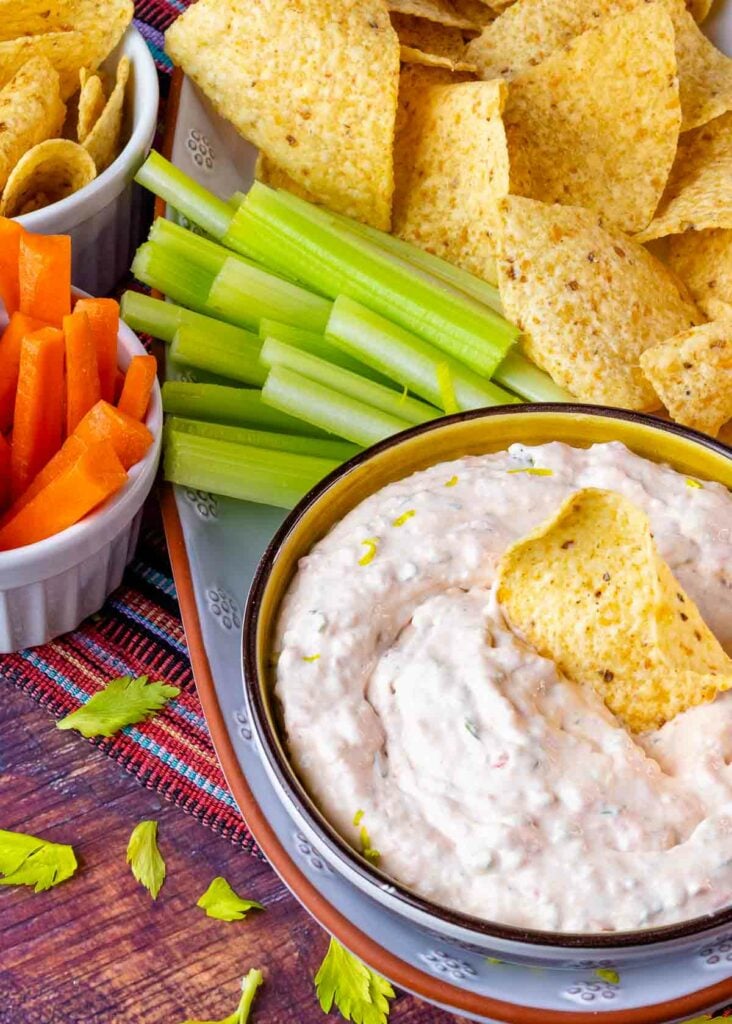 Bowl of Southwest Ranch Dip on a platter with celery sticks and tortilla chips.