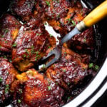 Crock Pot Chicken Thighs in bowl of pot with serving fork.