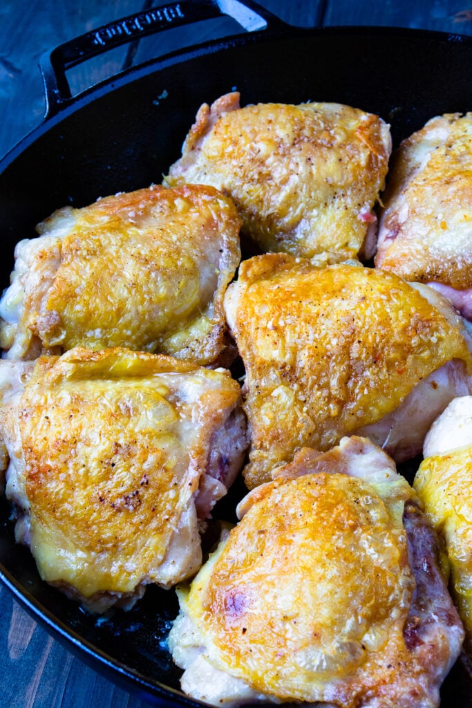 Seared chicken thighs in a cast iron skillet for Crock Pot Chicken Thighs recipe.