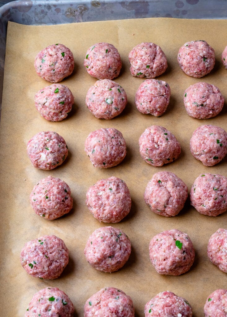 Homemade Meatballs made with ground beef rolled into balls on a sheet pan.