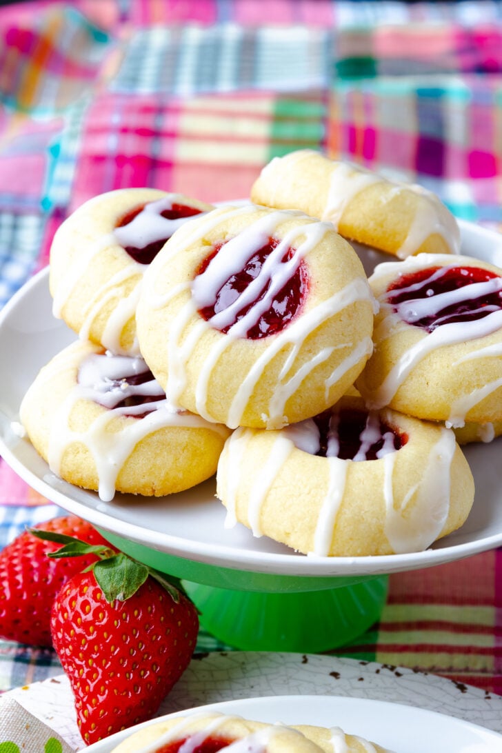 6 Jam Thumbprint Cookies on a small cake stand served with strawberries.