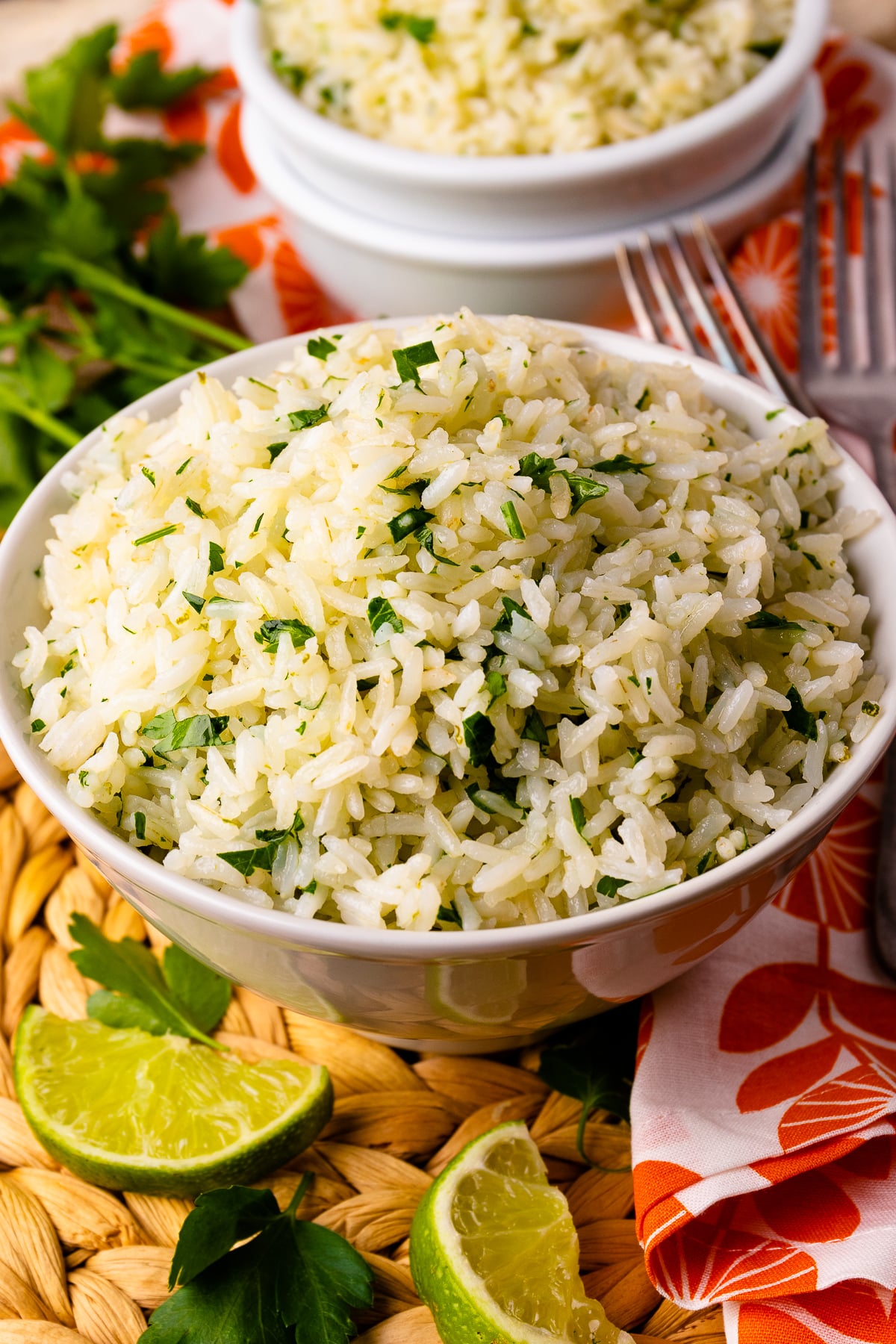Instant Pot Coconut Lime Rice in white bowl garnished with fresh cilantro and lime wedges, served with forks
