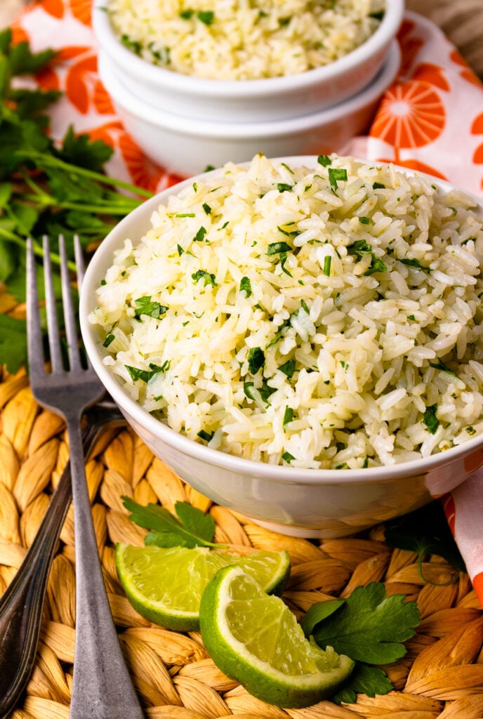 Bowl of Instant Pot Coconut Lime Rice with lime wedges and forks.