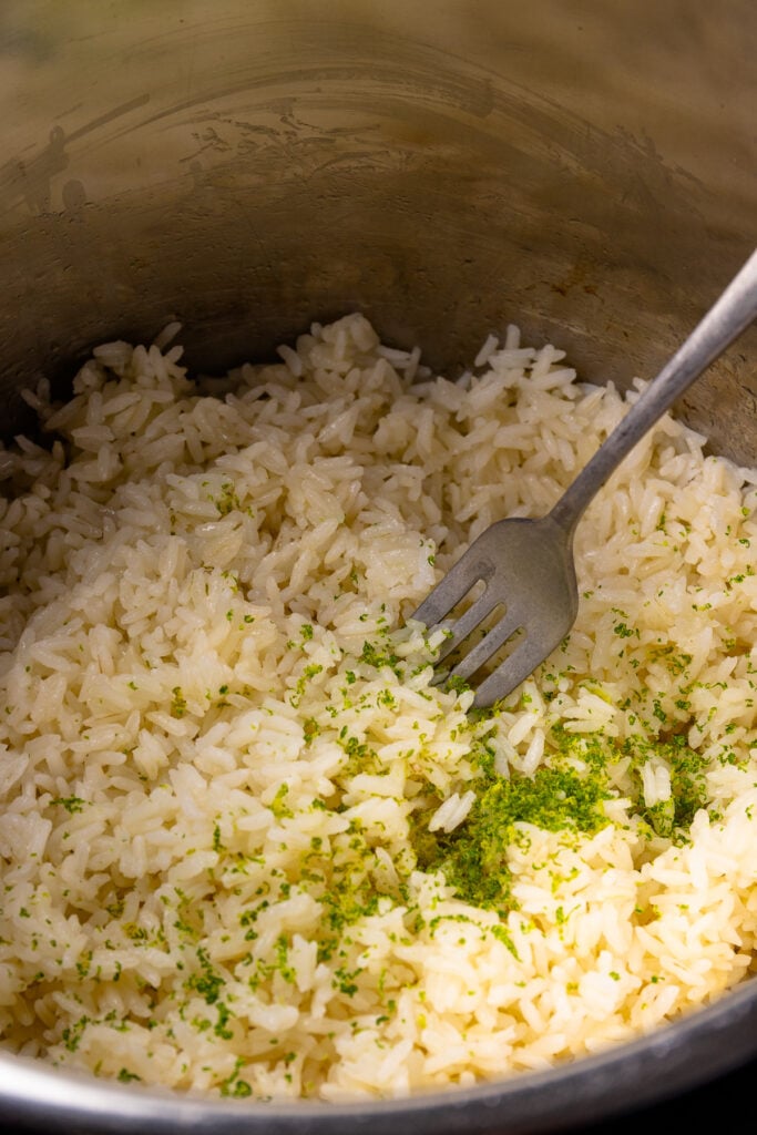 Instant Pot Coconut Rice with lime zest in a pot with fork.