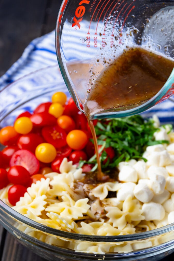 Balsamic herb dressing poured over fresh ingredients make Caprese Pasta Salad so delicious.
