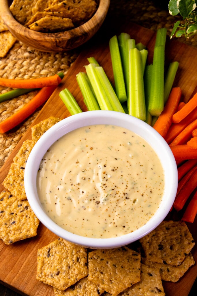 Bowl of Garlic Herb Tahini Dressing with carrots, celery and crackers.