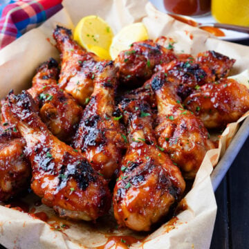 Grilled BBQ Chicken Legs with sauce and lemons.