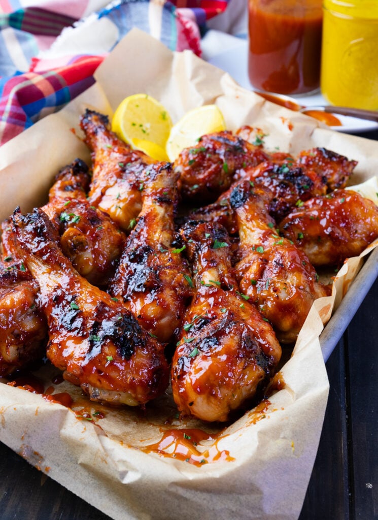 Grilled BBQ Chicken Legs with sauce and lemons.