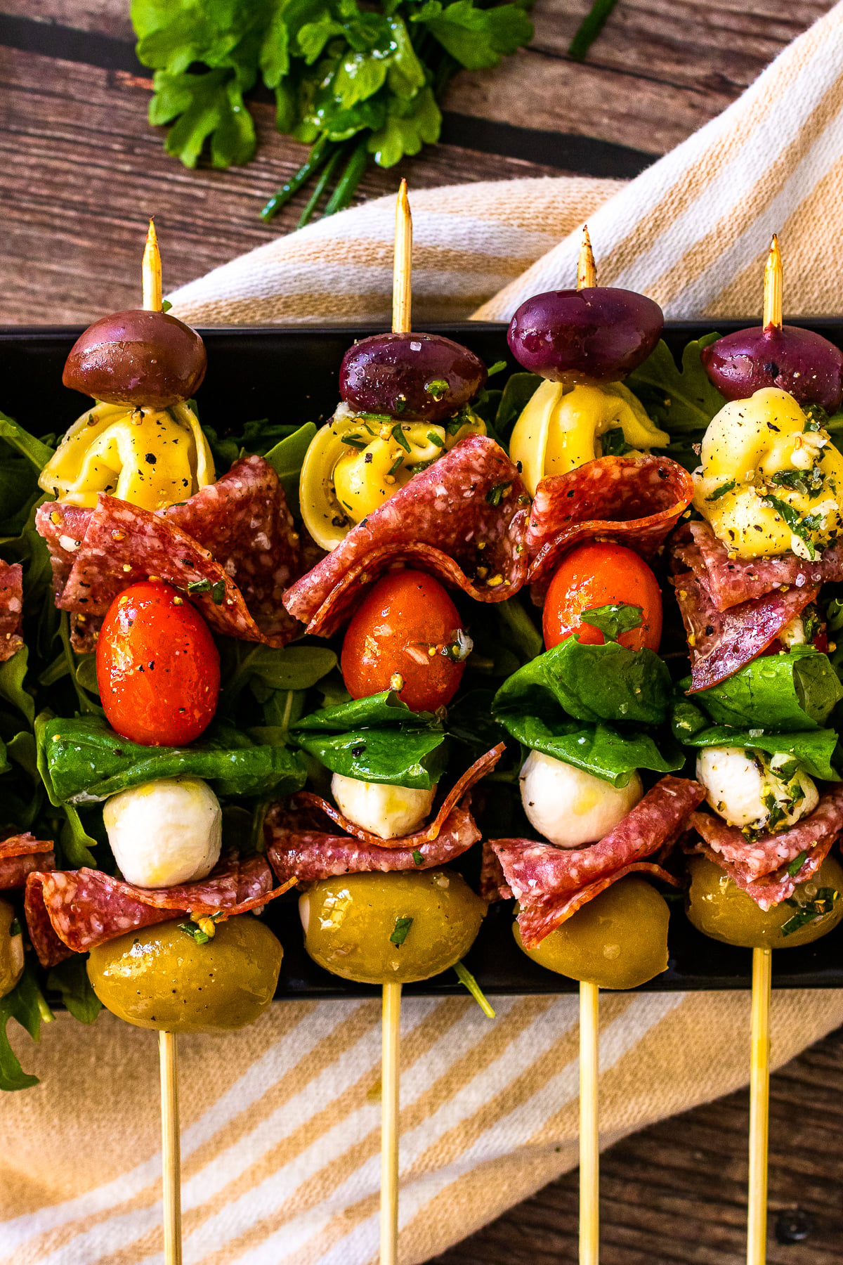 Antipasto skewers with olives and pasta lined up on a serving platter.