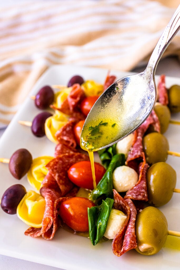 Homemade vinaigrette dressing drizzled over antipasto skewers