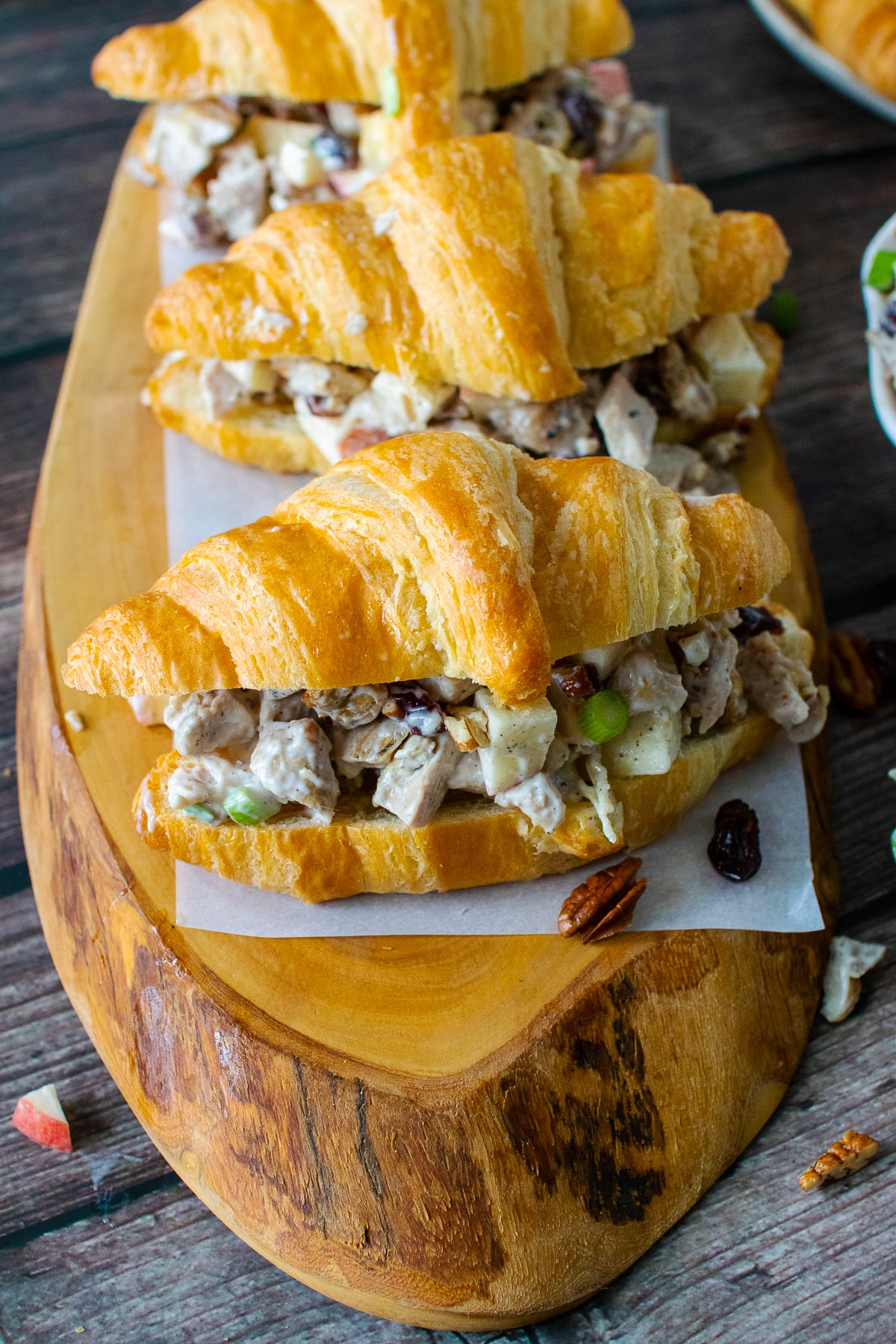 Three Cranberry Pecan Chicken Salad Croissants on a board.