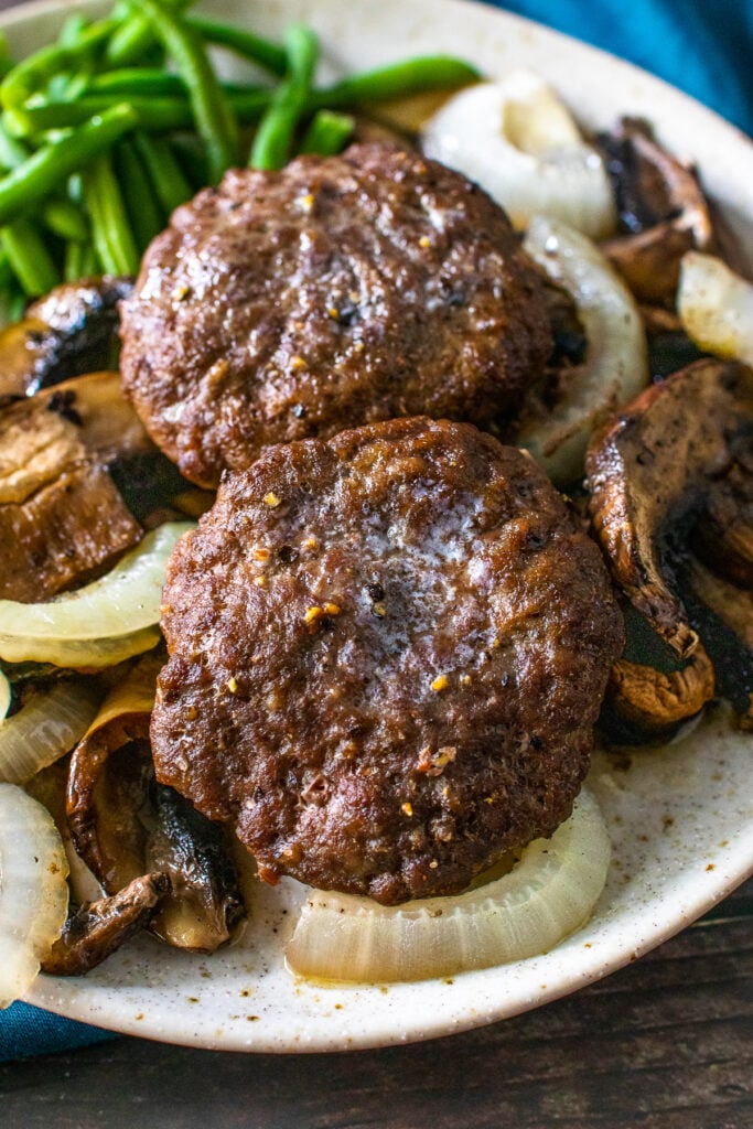 2 hamburger steak patties served with buttery sauteed onions and mushrooms, with delicious green beans as a side dish.