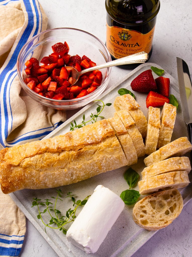 Ingredients for strawberries and herb goat cheese on toasted bread.