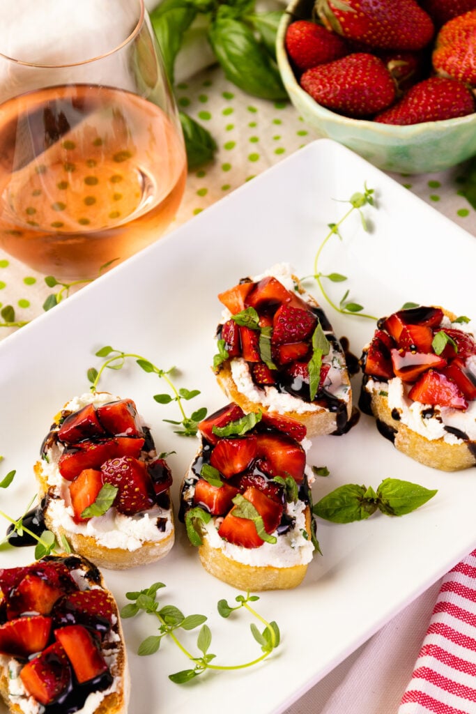 Strawberry Goat Cheese Bruschetta with rose wine on a whtie serving plate.