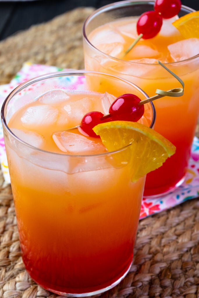 2 glasses of Tequila Sunrises with cherries and oranges.