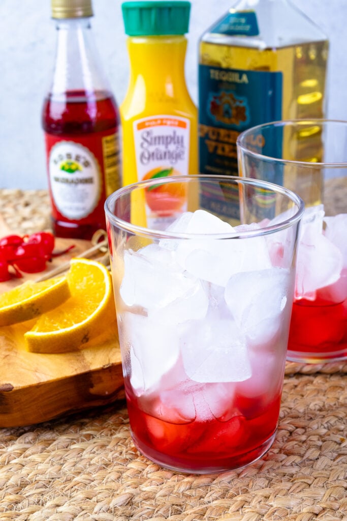 Glassses with ice and grenadine for Tequila Sunrises.