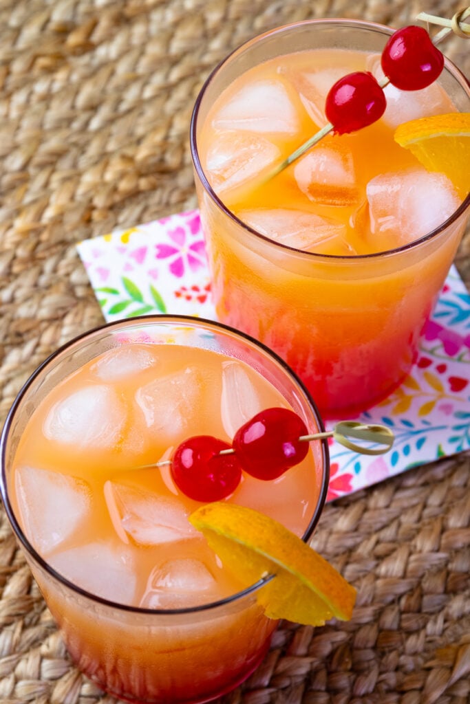 Refreshing Tequila Sunrise in a glass served over ice with pretty napkins.