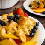French Toast Bread Pudding on a plate with peaches and berries.