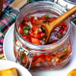 Tomato Relish in a jar with a wooden spoon for serving.