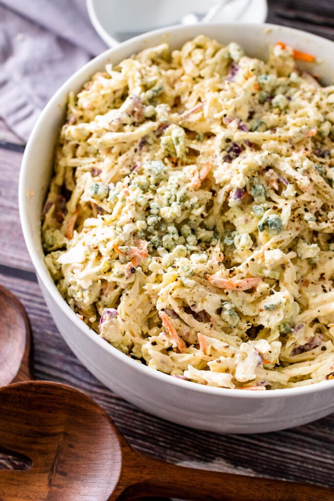 Blue Cheese Coleslaw in a large white bowl with wooden spoon