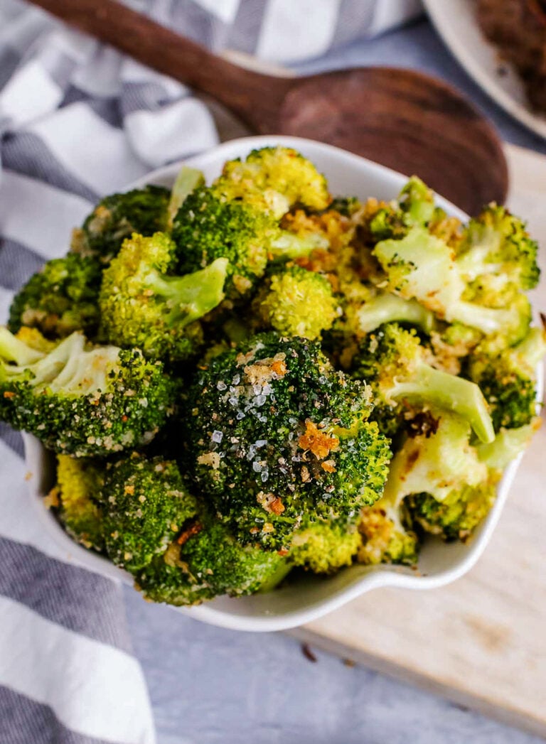 Super easy roasted broccoli bowl close-up showing seasoned florets with garlic and red pepper flakes in white dish