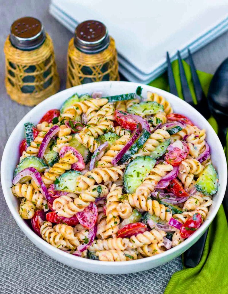 Creamy Tomato Cucumber Pasta Salad made with a simple dressing with fresh herbs and red onions.